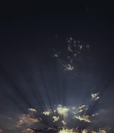 Sunset with dramatic clouds and sun rays breaking through, creating a serene and picturesque evening sky.