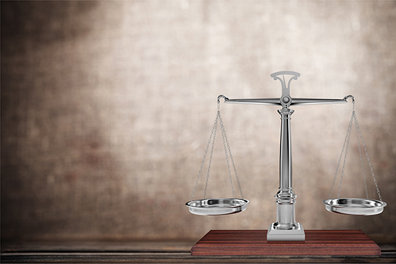 Silver balance scale on a wooden table, symbolizing justice and fairness against a textured brown background.