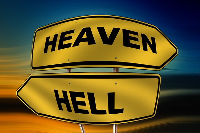 Yellow signposts with Heaven and Hell directions against a blurred background, symbolizing choices and paths.