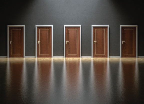 Five closed wooden doors in a dimly lit room with reflections on the shiny floor, symbolizing choices and decisions.