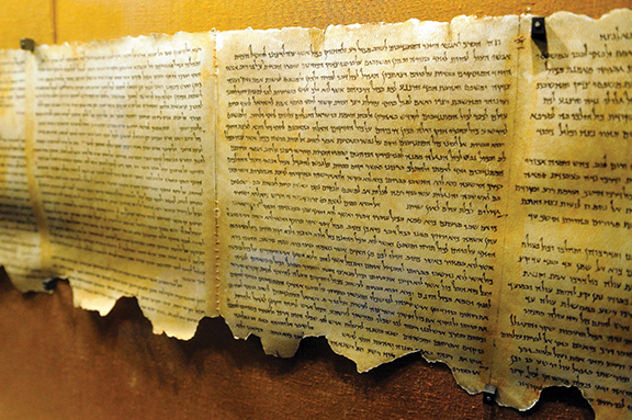 Ancient historical scroll with Hebrew text displayed in a museum exhibit.