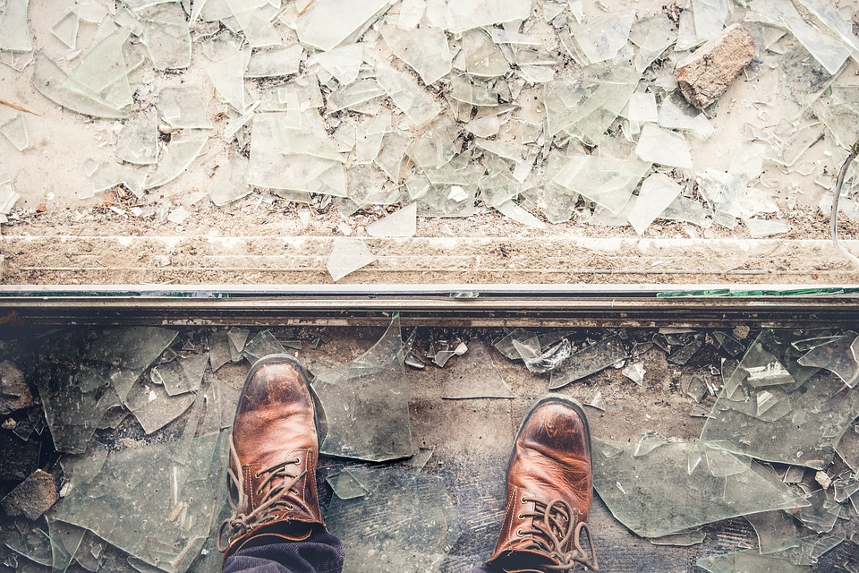 man standing beside broken glass