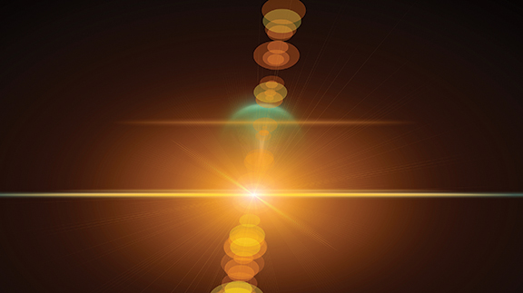 Abstract glowing light burst with lens flare and bokeh effects, on a dark background.