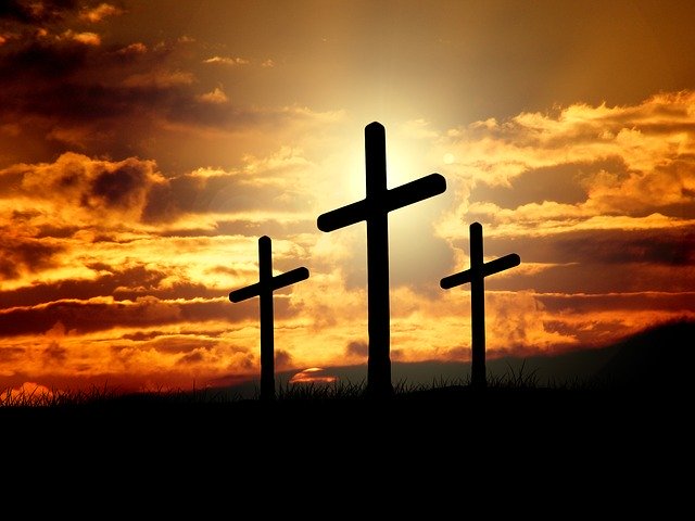 Three crosses silhouetted against a dramatic sunset sky, symbolizing faith and hope.