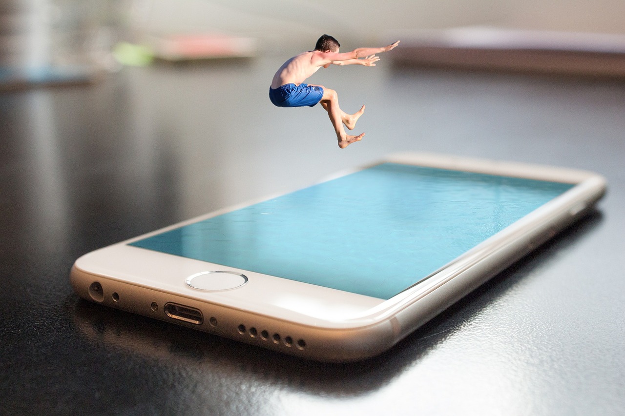 Man in blue shorts jumping into a smartphone pool, symbolizing digital immersion and connectivity.