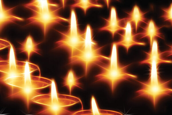 Glowing candle flames in darkness create a serene, warm ambiance, perfect for peaceful meditation or relaxation.