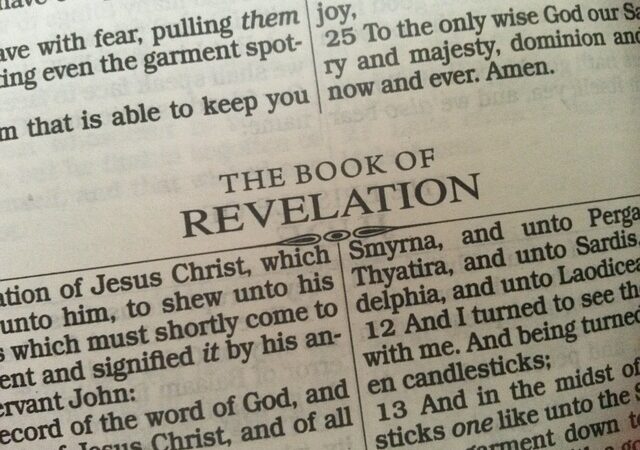Close-up of a Bible open to the Book of Revelation, featuring text from the New Testament scriptures.