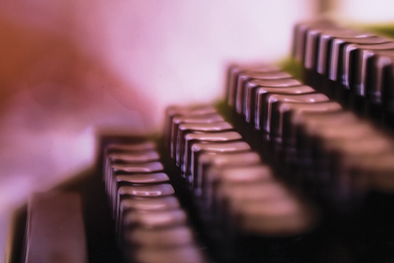 Close-up of vintage typewriter keys in soft focus with a warm, nostalgic color palette.
