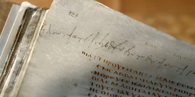 Ancient manuscript close-up showing handwritten Greek text on aged paper.