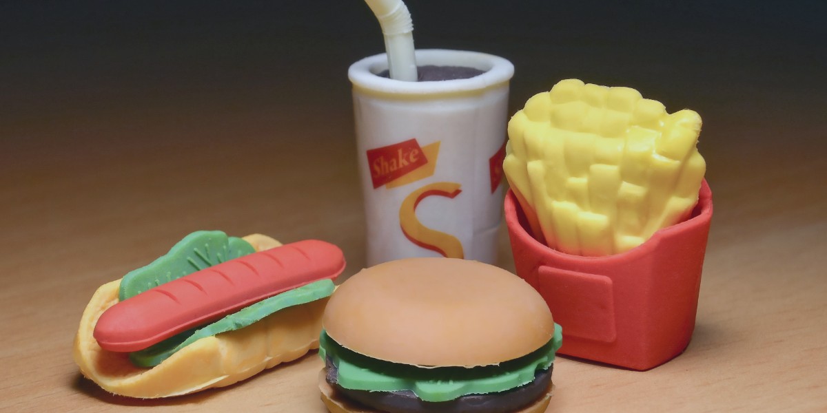 Toy fast food items: hamburger, hot dog, fries, and drink on a wooden surface. Fun and colorful play set.