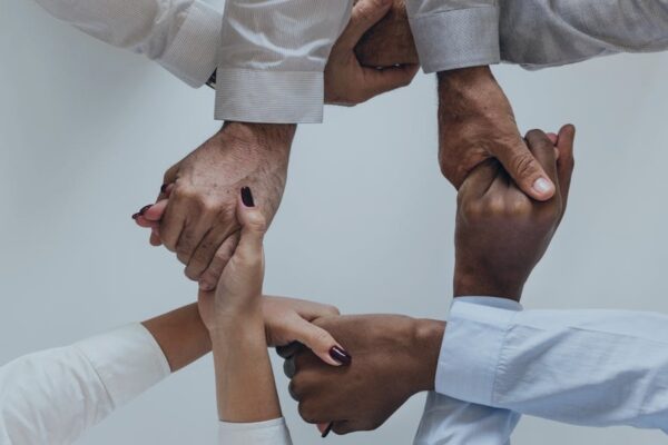 Diverse group of hands joined together symbolizing teamwork and unity against a neutral background.