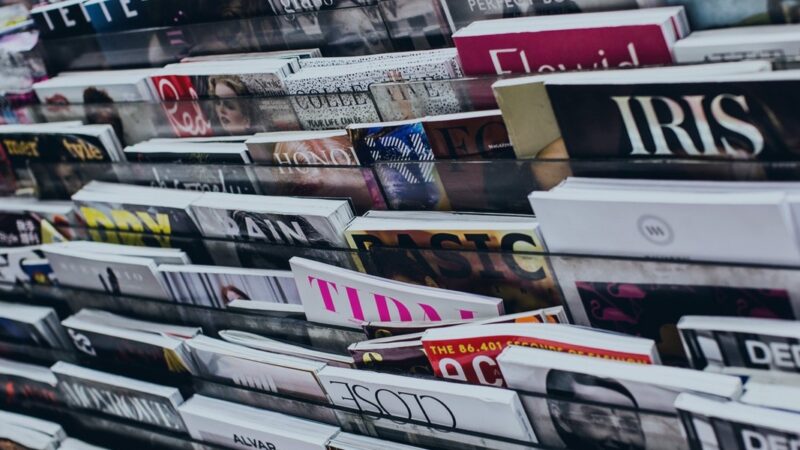 Magazines displayed on a rack, showcasing diverse covers and titles in a bookstore or newsstand setting.