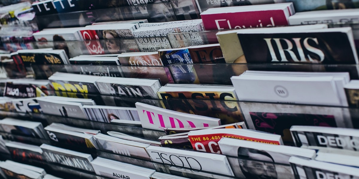 Magazines displayed on a rack, showcasing diverse covers and titles in a bookstore or newsstand setting.