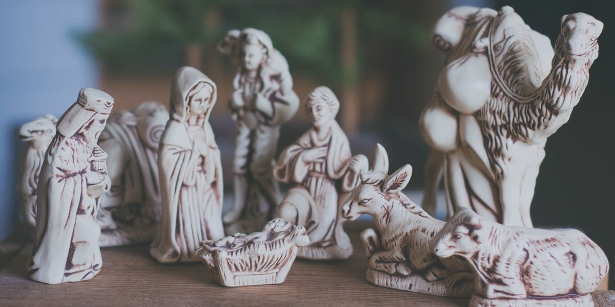 Nativity scene figurines with Mary, Joseph, baby Jesus, and animals on a wooden table, capturing a serene holiday moment.