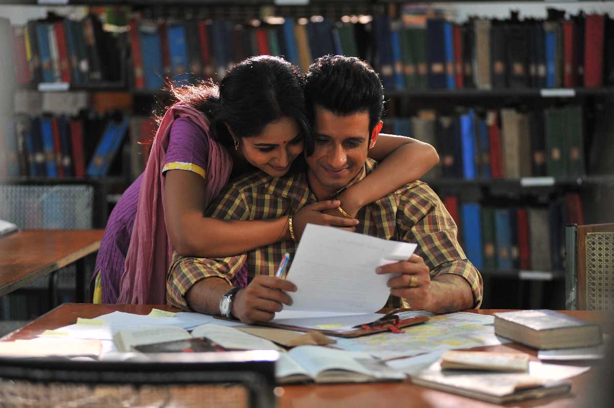 Couple reading and embracing in a library, surrounded by books and papers, with shelves in the background.