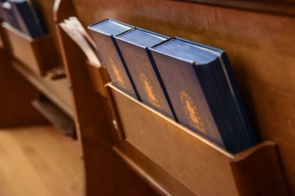 Hymnals in a wooden pew slot at a church, highlighting religious service preparation and seating arrangement.