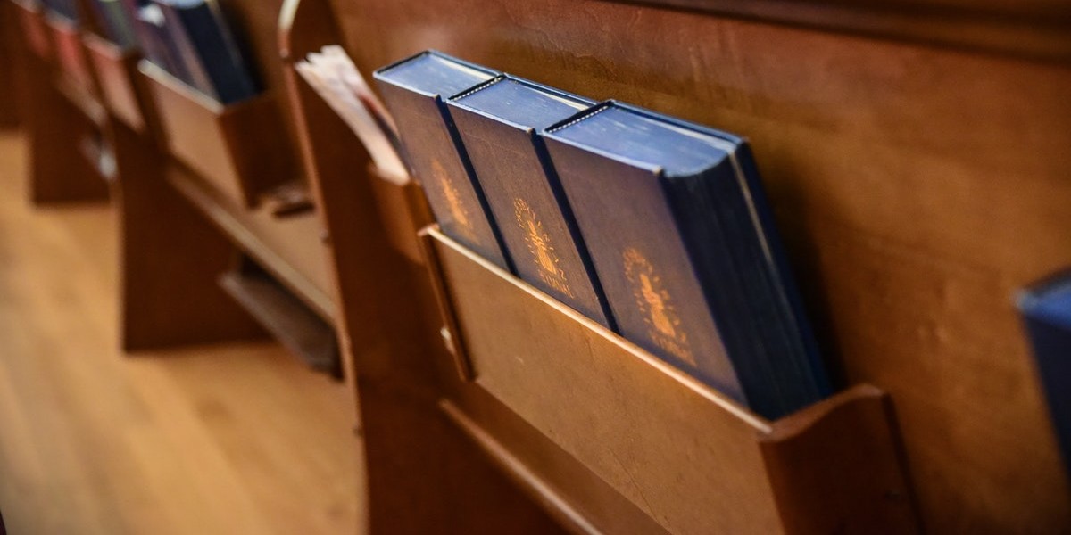 Hymnals in a wooden pew slot at a church, highlighting religious service preparation and seating arrangement.