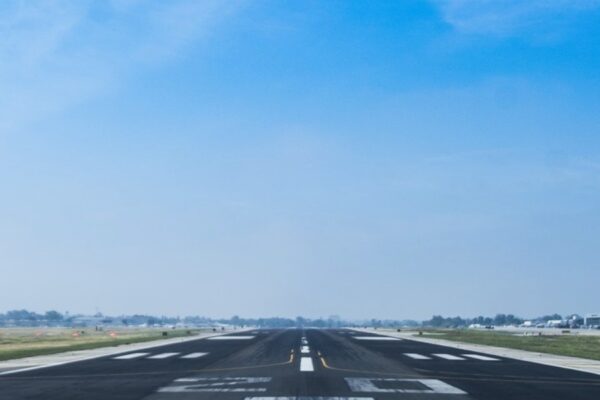 Wide airport runway under a clear blue sky, ready for aircraft takeoff.