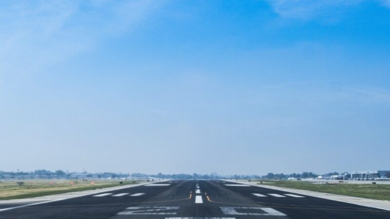 Wide airport runway under a clear blue sky, ready for aircraft takeoff.