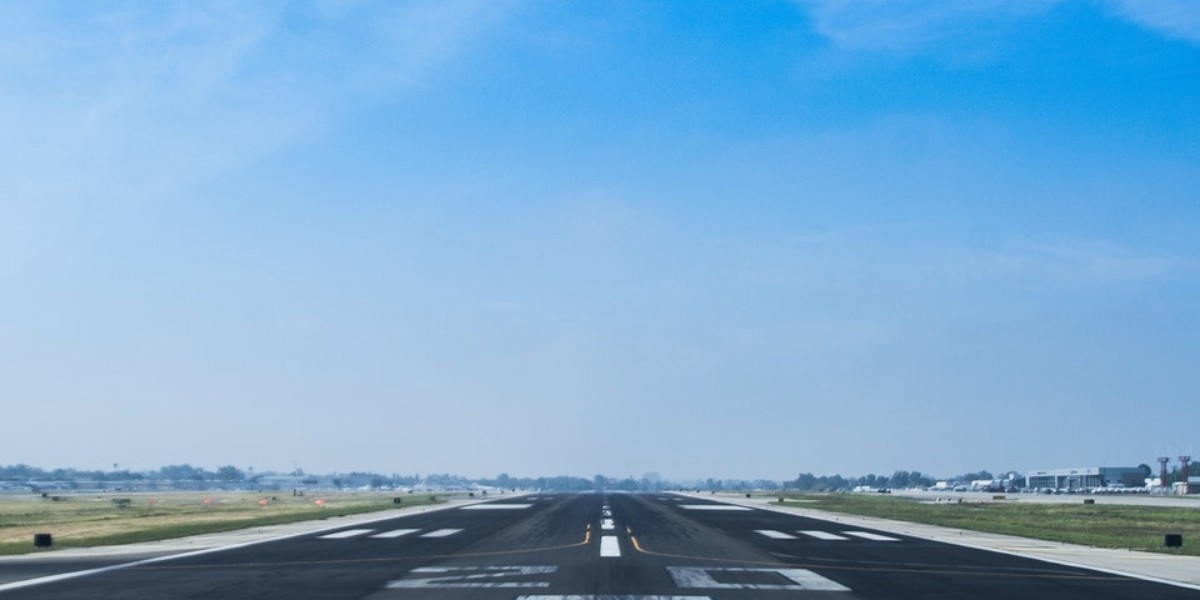 Wide airport runway under a clear blue sky, ready for aircraft takeoff.