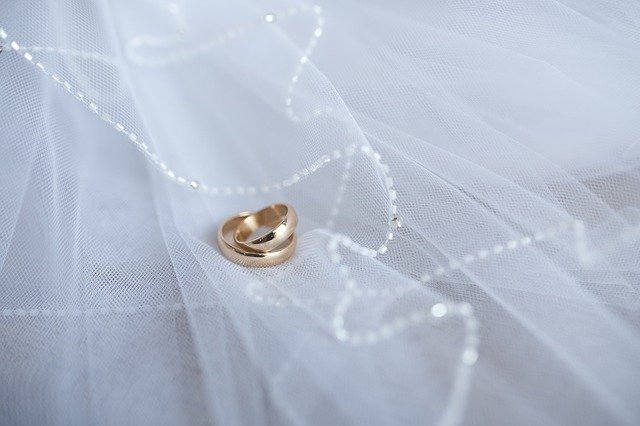 Two gold wedding rings on white tulle fabric, symbolizing love and marriage.