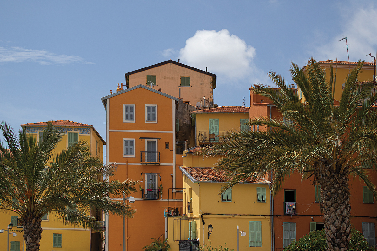 Colorful Mediterranean houses with palm trees under a clear blue sky.