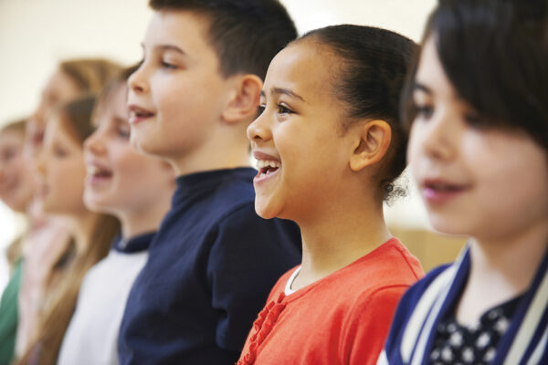 Children singing happily in a choir, showcasing diverse expressions and joy in a classroom setting.
