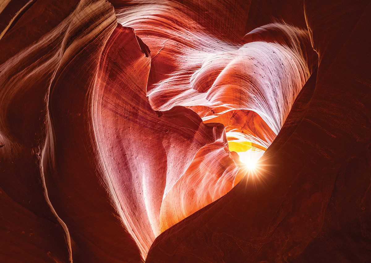 Sunlight streams through sandstone curves in Antelope Canyon, highlighting rich reds and textures.