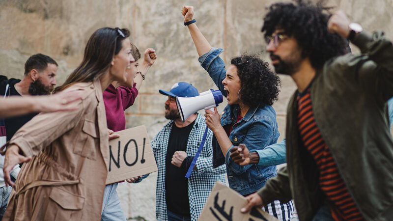 Protesters shouting with signs and megaphone in a passionate demonstration for change.