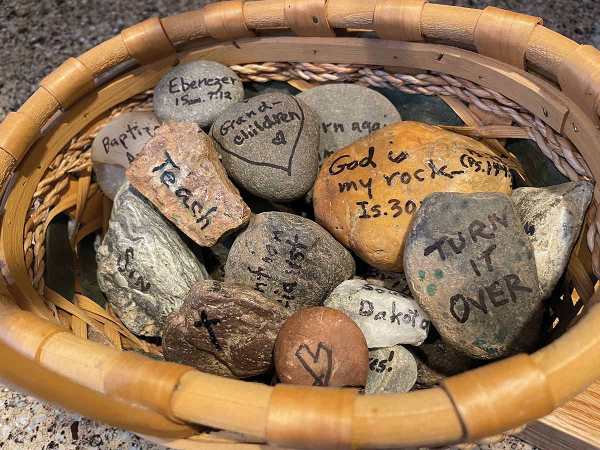 Basket of engraved gratitude stones with motivational words and Bible verses, inspiring reflection and mindfulness.