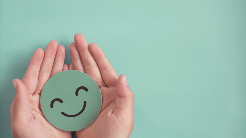 Hands holding green happy smile face paper cut, good feedback rating and positive customer review, experience, satisfaction survey ,mental health assessment, child wellness,world mental health day concept