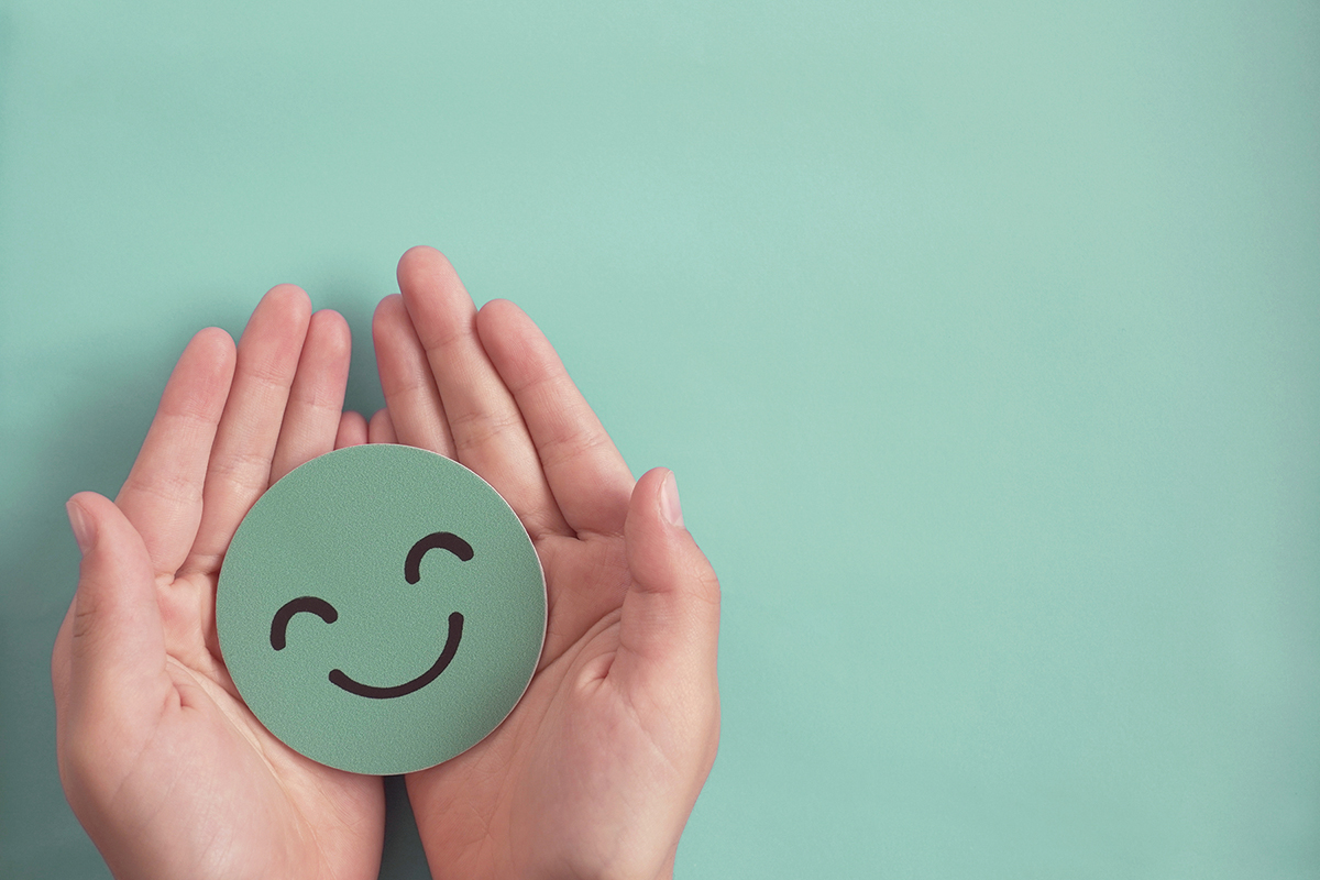 Hands holding green happy smile face paper cut, good feedback rating and positive customer review, experience, satisfaction survey ,mental health assessment, child wellness,world mental health day concept