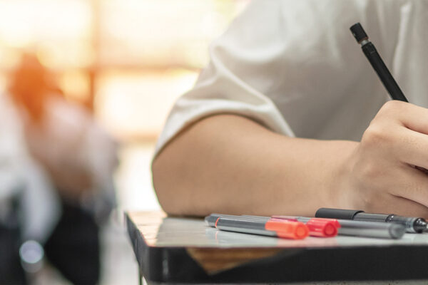 Exam at school with student's taking educational admission test in class, thinking hard, writing answer in university classroom, education and world literacy day concept