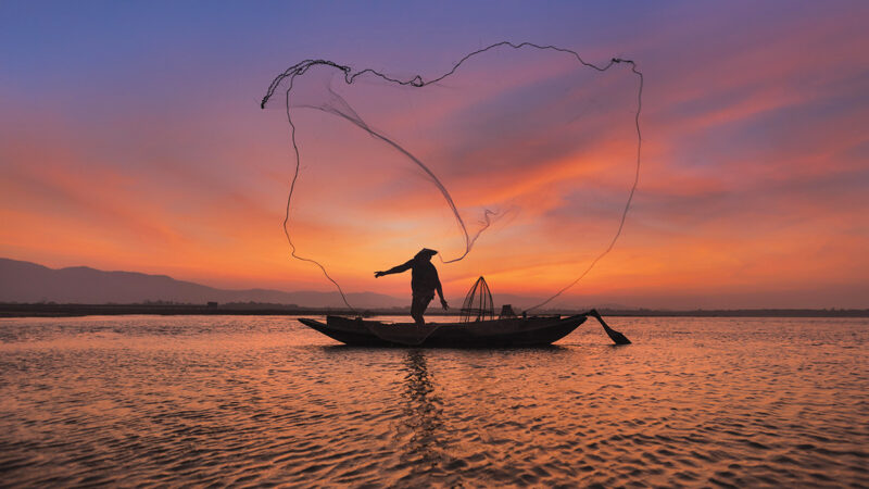 Asian Fisherman With His Wooden Boat In Nature River At The Early Morning Before Sunrise